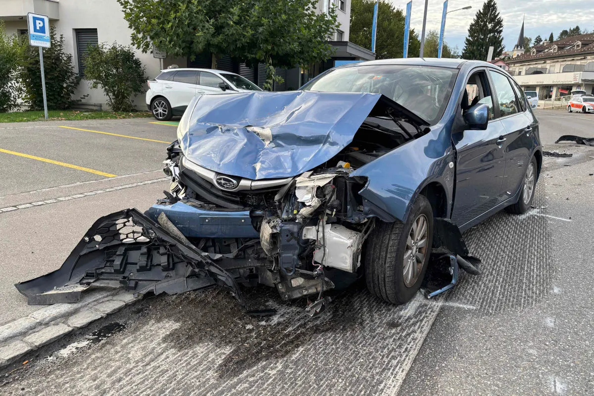 Das Bild zeigt ein blaues Auto mit stark eingedrückter Front, das am Straßenrand steht. Der Unfall fand in einer Wohngegend statt, es sind keine Personen sichtbar.