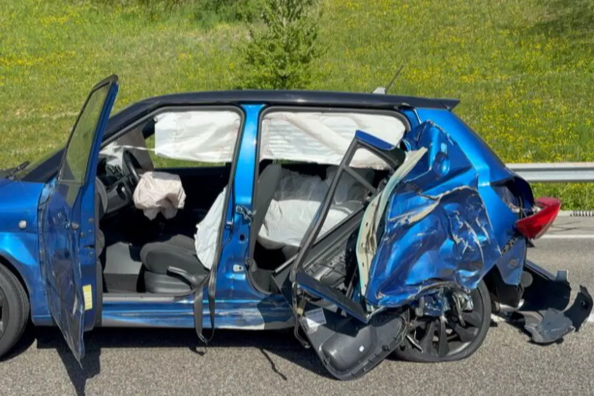 Ein stark beschädigtes blaues Auto steht auf einer Straße. Die Tür ist geöffnet und die Airbags sind ausgelöst.