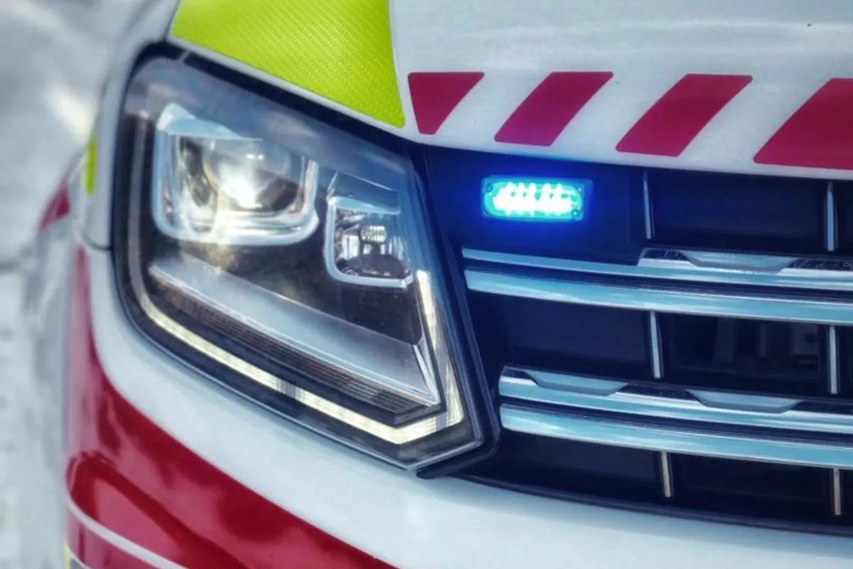 Die Aufnahme zeigt die Front eines Einsatzfahrzeugs mit einem aktiven blauen Licht und roten Streifen. Es ist auf einer verschneiten Straße geparkt.