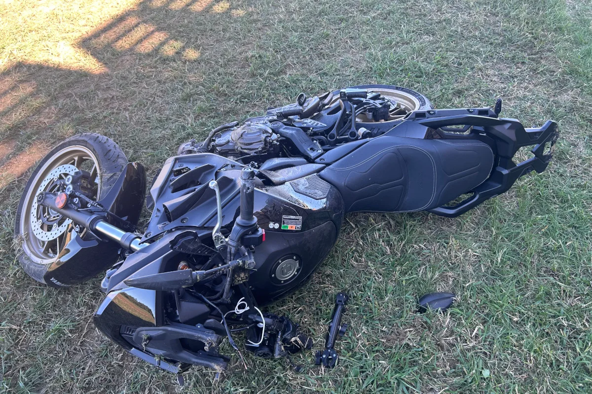 Ein schwarzes Motorrad liegt beschädigt auf einer grünen Wiese. Einzelteile sind um das Motorrad verstreut.
