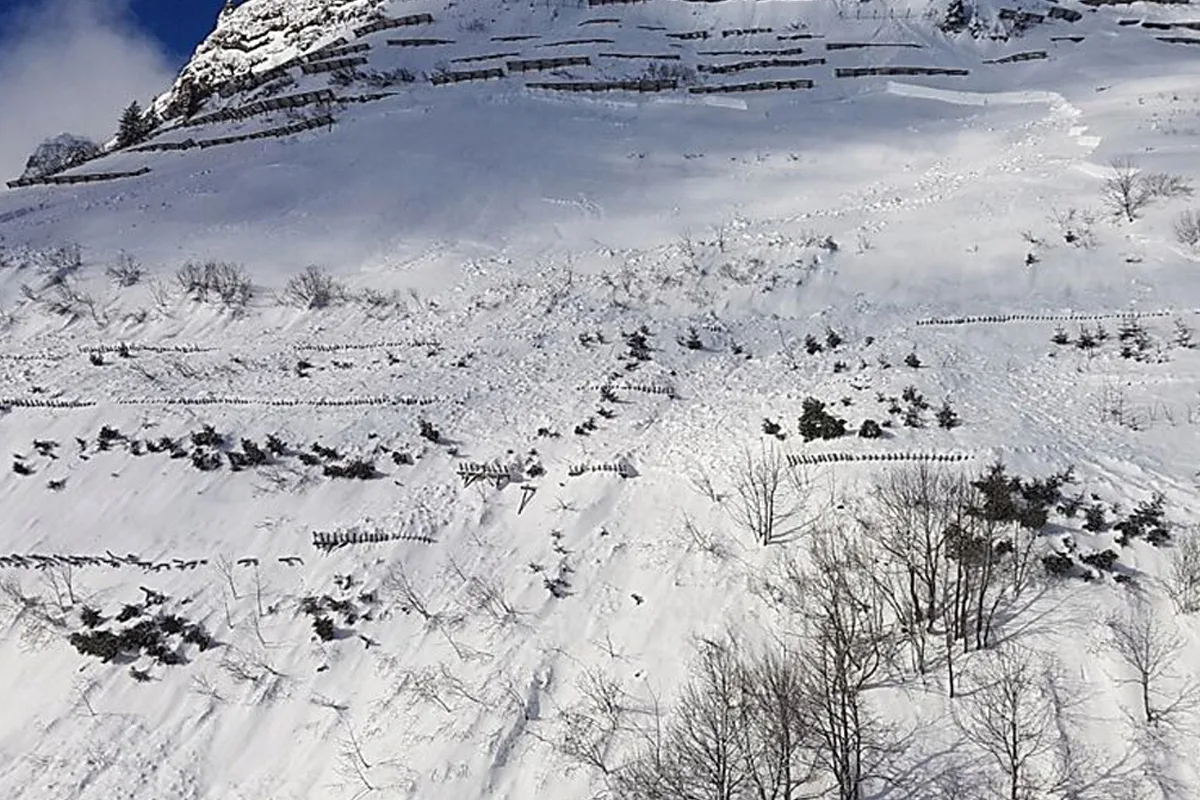 Eine verschneite Berglandschaft mit mehreren Reihen von Verbauungen gegen Lawinen. Oben Schnee und vereinzelt Vegetation.