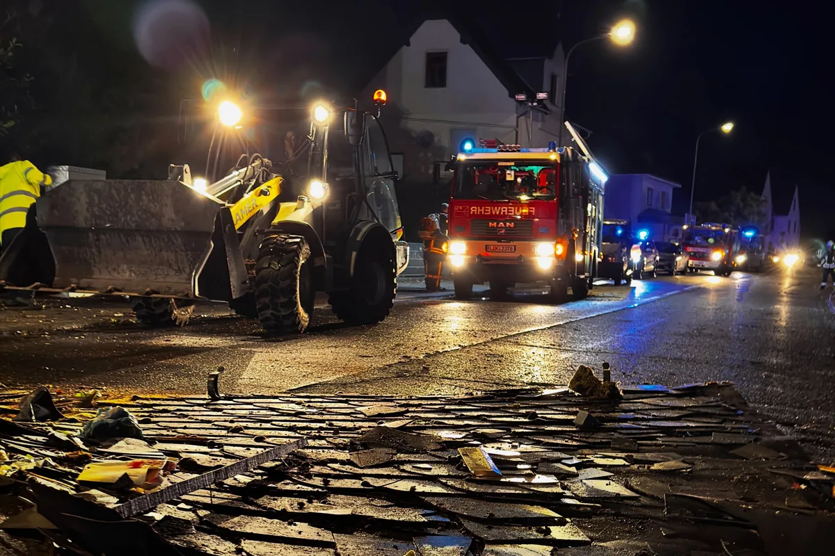 In der Nacht sind ein Feuerwehrfahrzeug und ein Räumfahrzeug auf einer Straße im Einsatz. Trümmer liegen auf dem Boden.