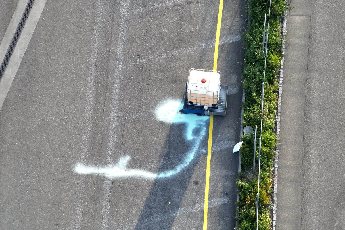 Ein Tankbehälter steht auf der Straße und hat eine blaue Flüssigkeit verschüttet, die sich über die Fahrbahn ausbreitet.