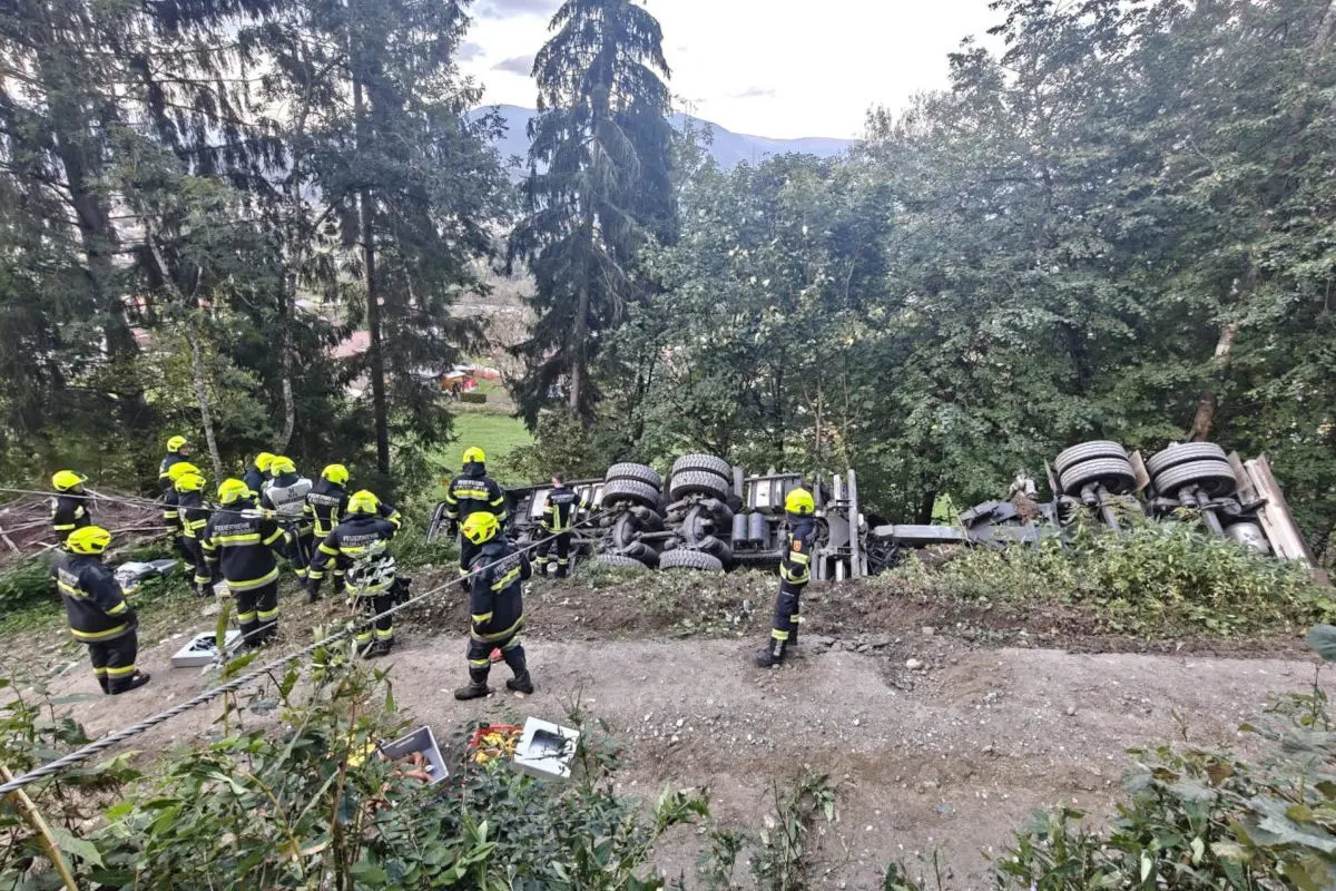 Ein Lastwagen liegt auf der Seite in einem Waldgebiet. Zahlreiche Feuerwehrleute in gelben Helmen arbeiten rund um das Fahrzeug.