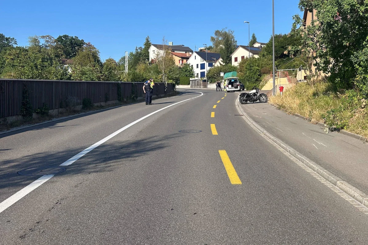 Ein Polizeifahrzeug steht auf einer kurvenreichen Straße, daneben ein Motorrad. Zwei Polizisten sind zu Fuß unterwegs.
