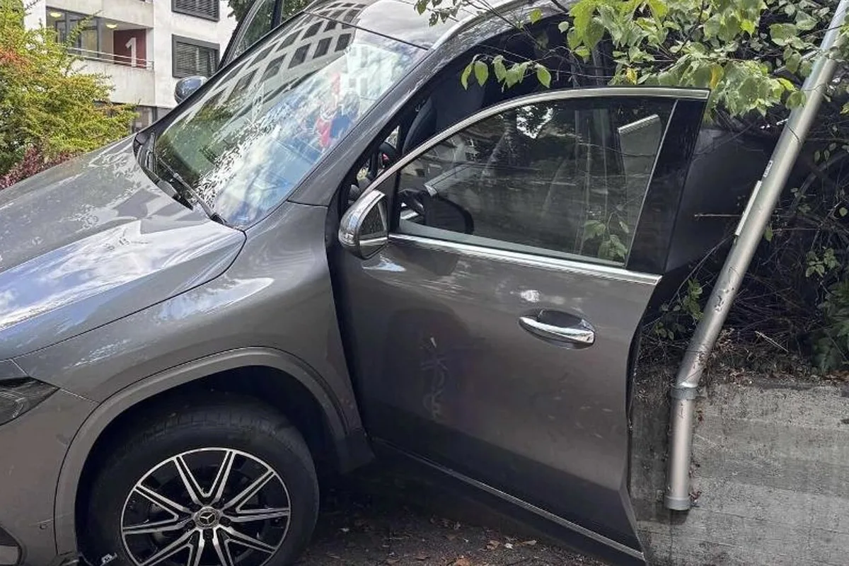 Ein grauer Geländewagen steht mit offenem Fahrerfenster in Büsche gefahren und hat einen Metallpfosten verbogen. Das Auto ist anscheinend in eine Mauer gefahren.