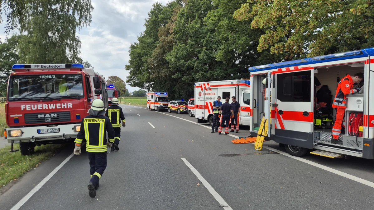 Mehrere Feuerwehr- und Rettungsfahrzeuge stehen entlang einer Landstraße. Einsatzkräfte sind in Aktion.