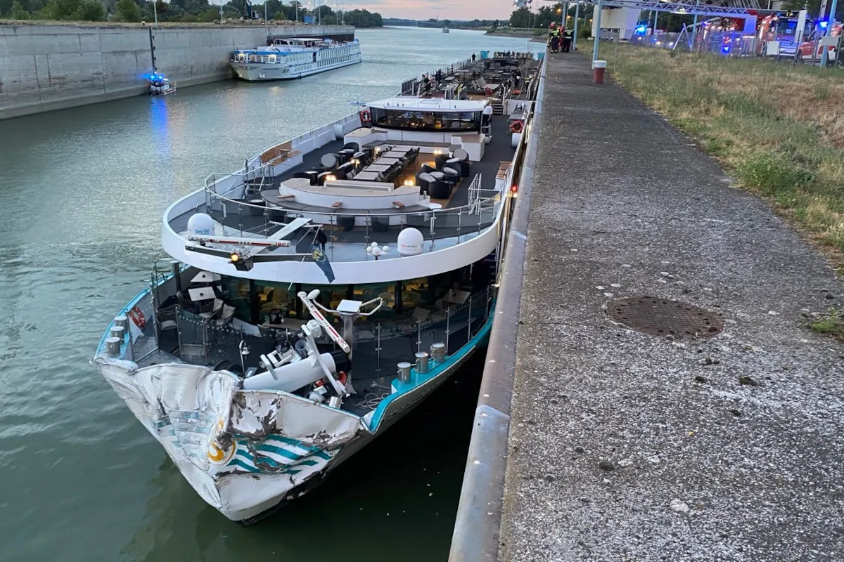 Ein Flusskreuzfahrtschiff mit beschädigtem Bug liegt am Rand eines Kanals. Polizei ist vor Ort zu sehen.