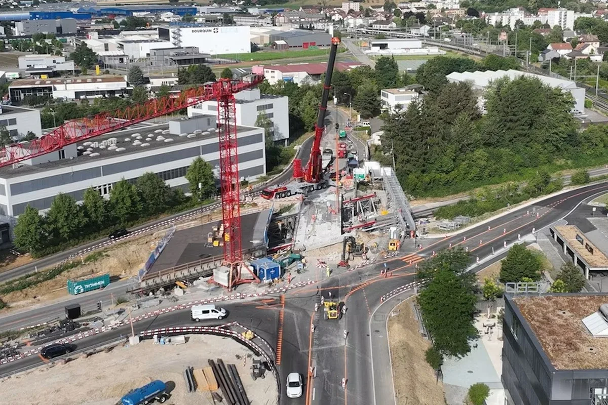 Das Bild zeigt eine Großbaustelle in einem Gewerbegebiet mit mehreren Kränen. Der Verkehr wird umgeleitet, da Bauarbeiten im Gange sind.