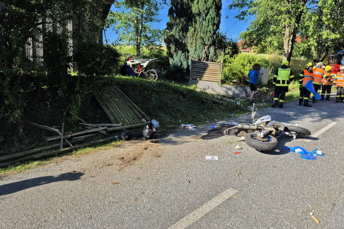 Ein verunfalltes Motorrad liegt auf der Straße, umgeben von Trümmern, während Feuerwehrleute die Unfallstelle sichern.