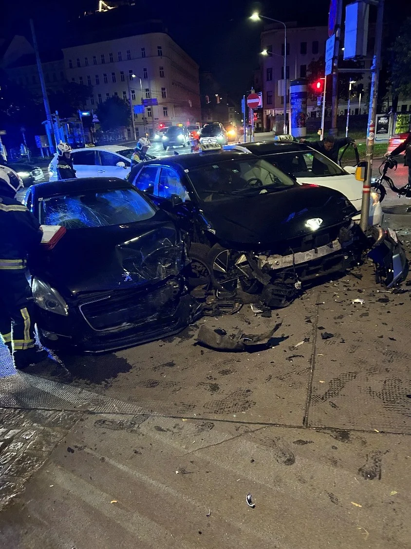 Zwei stark beschädigte Autos stehen bei Nacht an einer Kreuzung. Rettungskräfte sind vor Ort zu sehen.