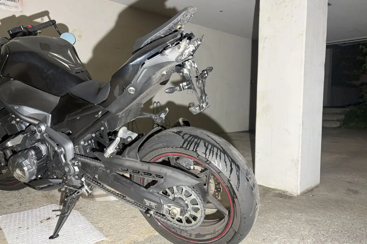 Ein Motorrad mit einem stark beschädigten Heck steht in einer Garage. Die Hinterradabdeckung ist verbogen.