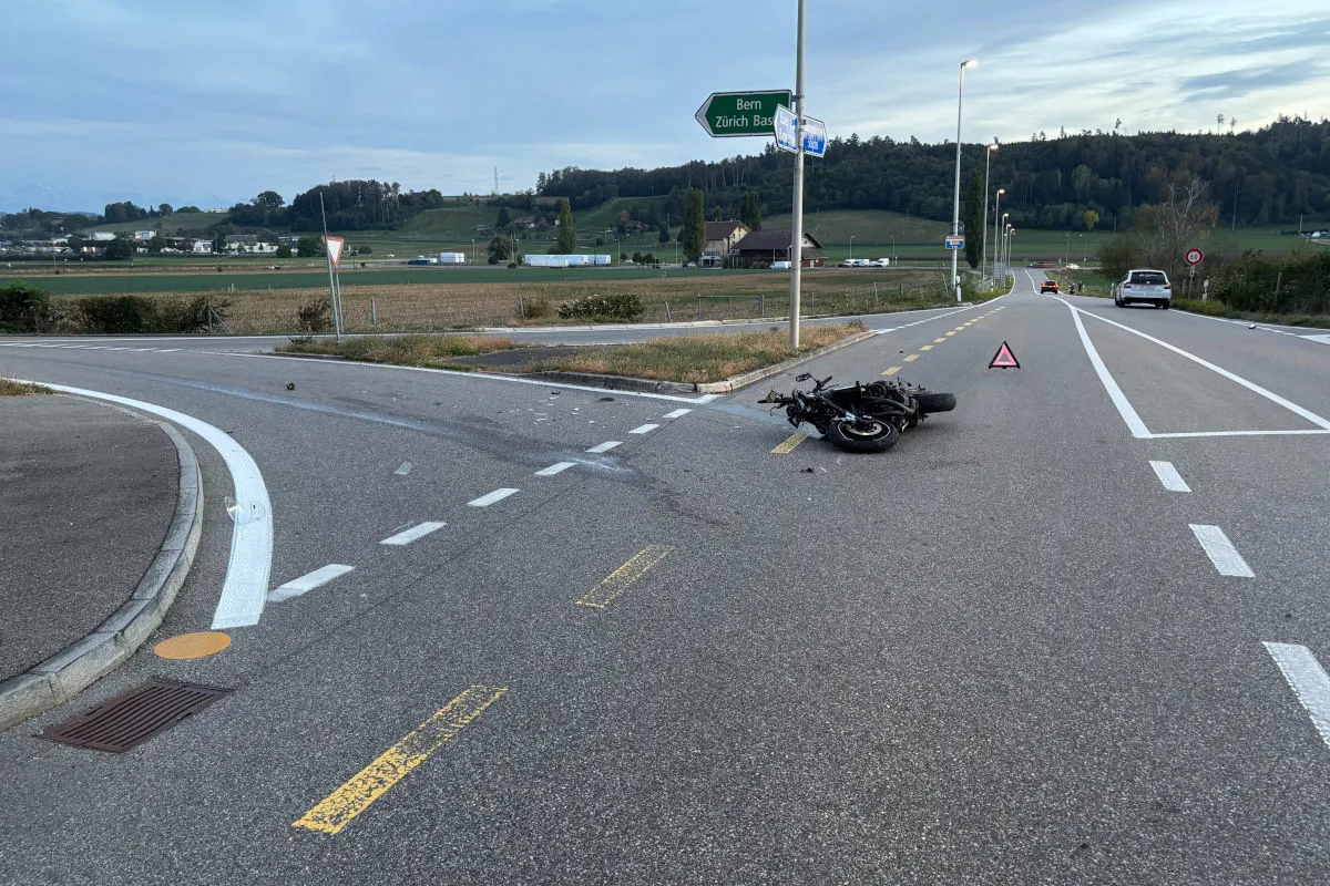 Ein beschädigtes Motorrad liegt auf einer Landstraße neben einem aufgestellten Warndreieck. Im Hintergrund sind Verkehrszeichen sichtbar, die Richtung Bern weisen.