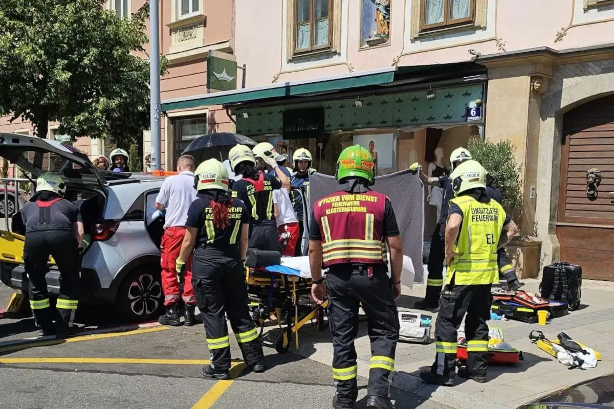 Mehrere Einsatzkräfte der Feuerwehr und Rettungsdienste versorgen Verletzte neben einem Pkw in einer städtischen Umgebung. Ein Rettungswagen ist geöffnet und Rettungsausrüstung ist am Boden verteilt.