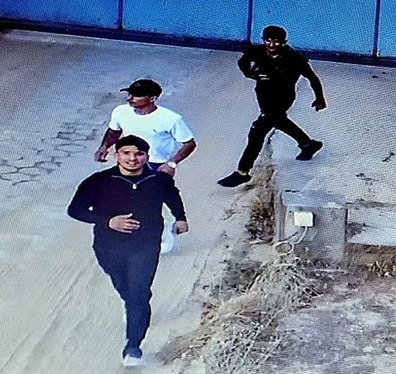 Das Bild zeigt drei Männer, die auf einem Weg entlanggehen. Sie wurden von einer Überwachungskamera aufgenommen.