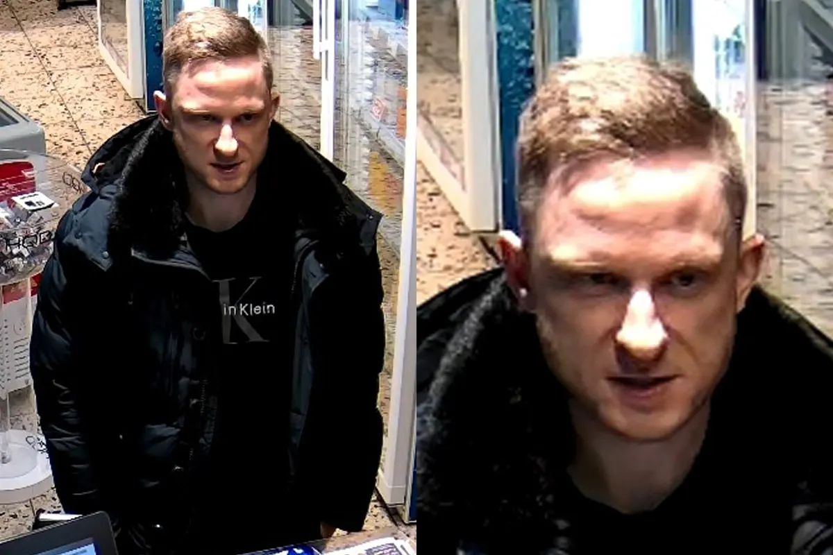 Überwachungskamera erfasst einen jungen Mann an einer Kasse in einem Geschäftsumfeld; er trägt eine dunkle Jacke.