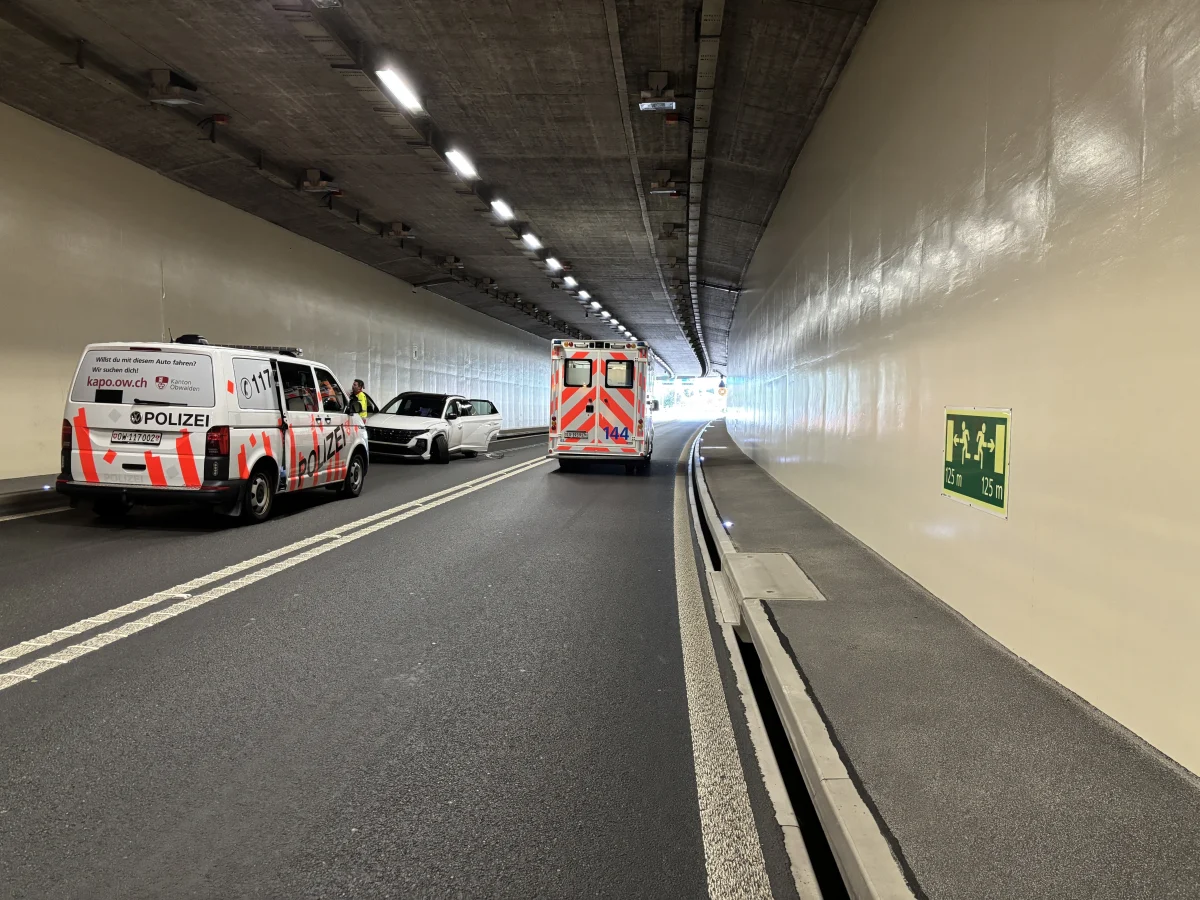 Ein Polizeifahrzeug und ein Krankenwagen stehen in einem Tunnel; ein weiteres Auto ist am Rand sichtbar.