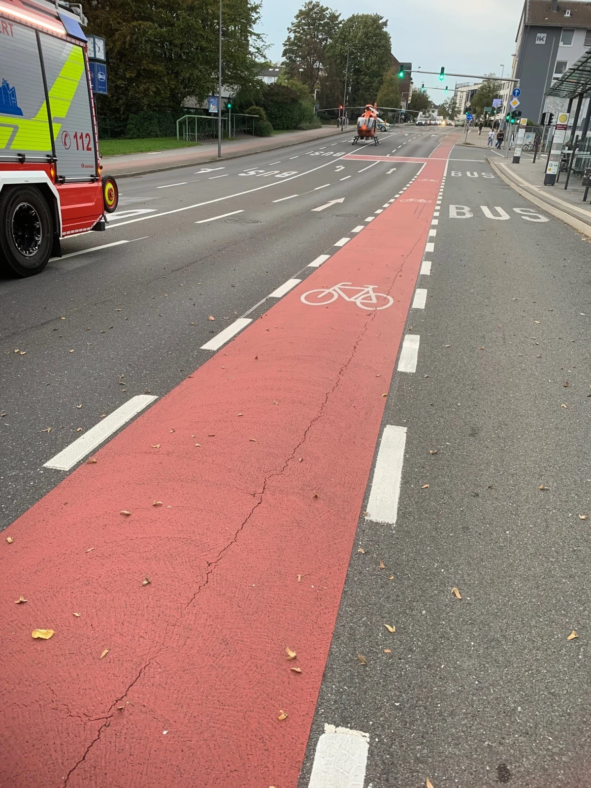 Ein Rettungshubschrauber ist auf der Straße bei einer Fahrradspur gelandet. Daneben steht ein Feuerwehrwagen.