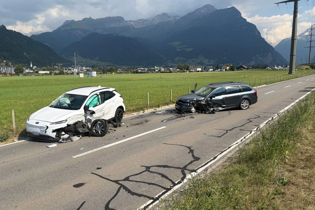 Zwei beschädigte Fahrzeuge stehen auf einer Landstraße nach einem Frontalzusammenstoß. Im Hintergrund sind Berge zu sehen.