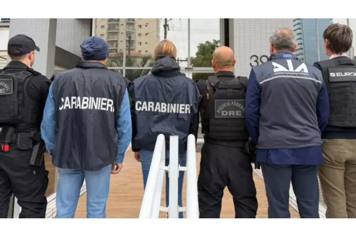 Eine Gruppe von Polizisten, alle in Uniformen mit unterschiedlichen Aufdrucken, steht mit dem Rücken zu einem modernen Gebäude.