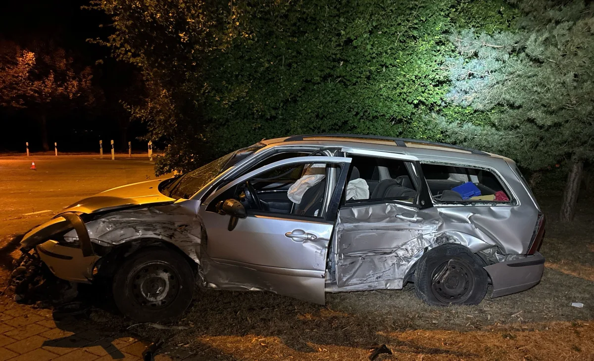 Ein stark beschädigter silberner Kombi steht am Straßenrand, mit geöffneten Airbags und eingedrückter Fahrerseite.