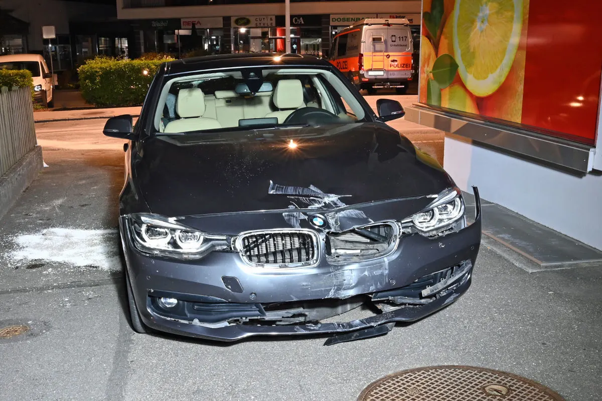 Ein grauer BMW mit deutlichen Frontschäden steht in einem Parkhaus. Im Hintergrund ist ein Polizeifahrzeug zu sehen.