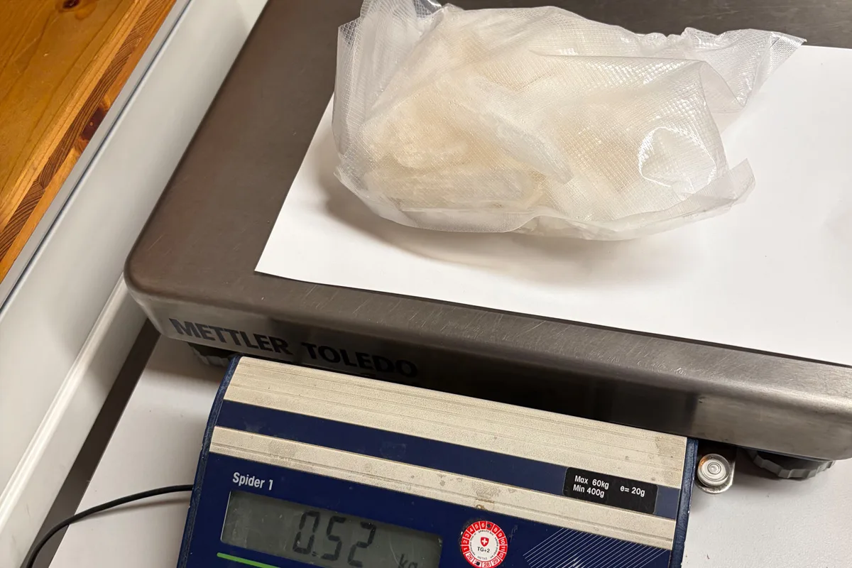 Ein in Folie verpacktes weißes Pulver liegt auf einer Waage. Die Waage zeigt ein Gewicht von 0,52 kg an.