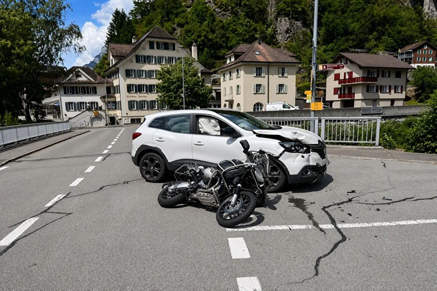 Auf der Straße liegt ein beschädigtes Motorrad vor einem weißen SUV. Im Hintergrund sind Wohnhäuser zu sehen.