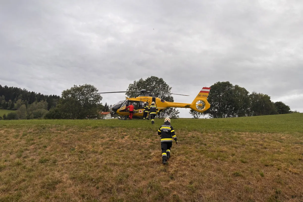 Ein gelber Rettungshubschrauber steht auf einer Wiese, umgeben von mehreren Einsatzkräften in Uniformen.