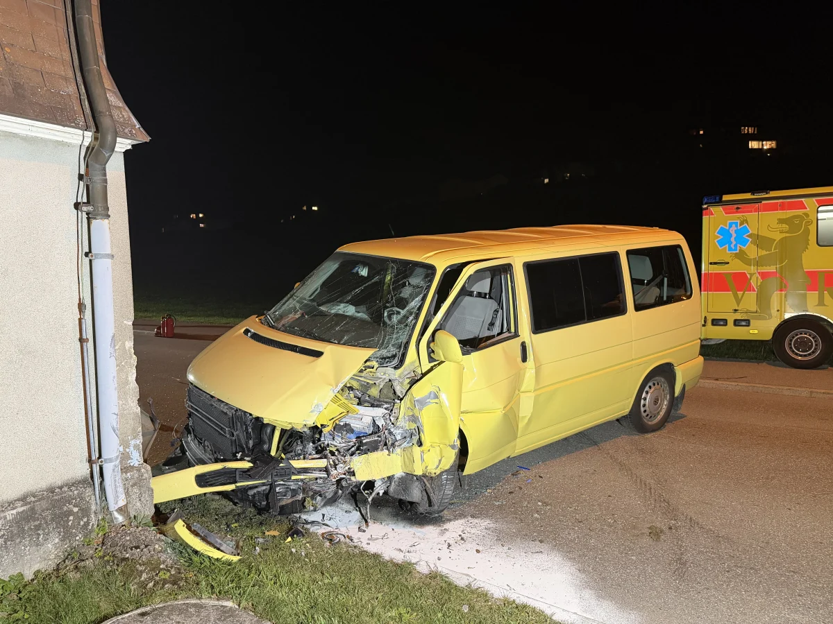 Ein gelber Van hat deutliche Frontschäden nach einem Aufprall an einer Hauswand. Im Hintergrund ist ein Rettungswagen zu sehen.