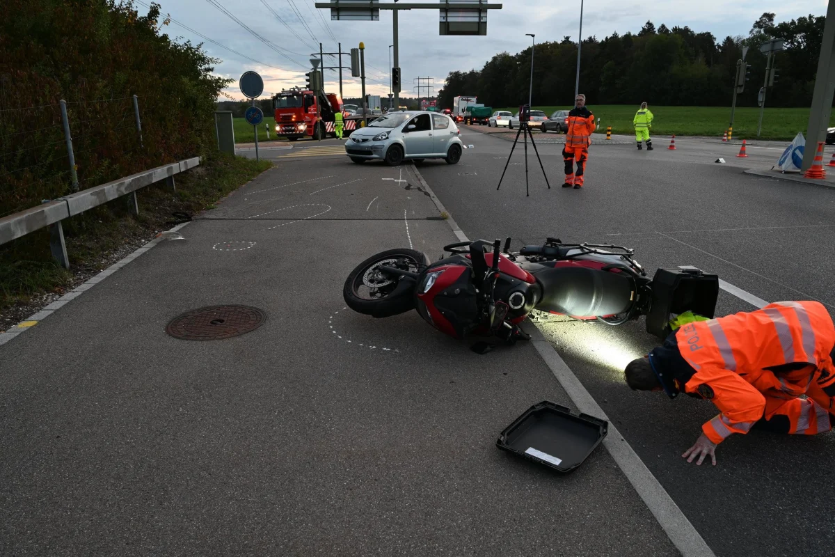 Ein umgestürztes Motorrad liegt auf der Straße nahe einer Kreuzung. Einsatzkräfte in Leuchtkleidung untersuchen die Unfallstelle.