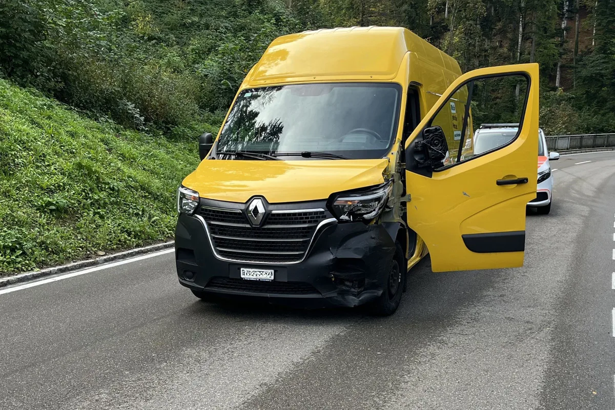 Ein gelber Renault Lieferwagen steht mit offenem Fahrerplatz und sichtbaren Frontschäden auf einer kurvigen Landstraße. Im Hintergrund ist ein weiteres Fahrzeug zu sehen.
