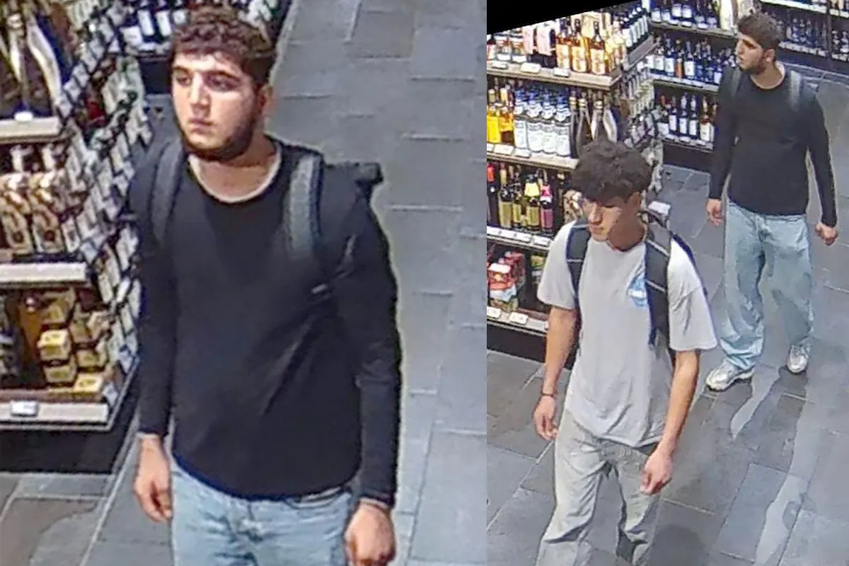 Zwei junge Männer mit Rucksäcken laufen durch ein Geschäft mit Regalen voller Produkte. Die Aufnahme stammt von einer Überwachungskamera.