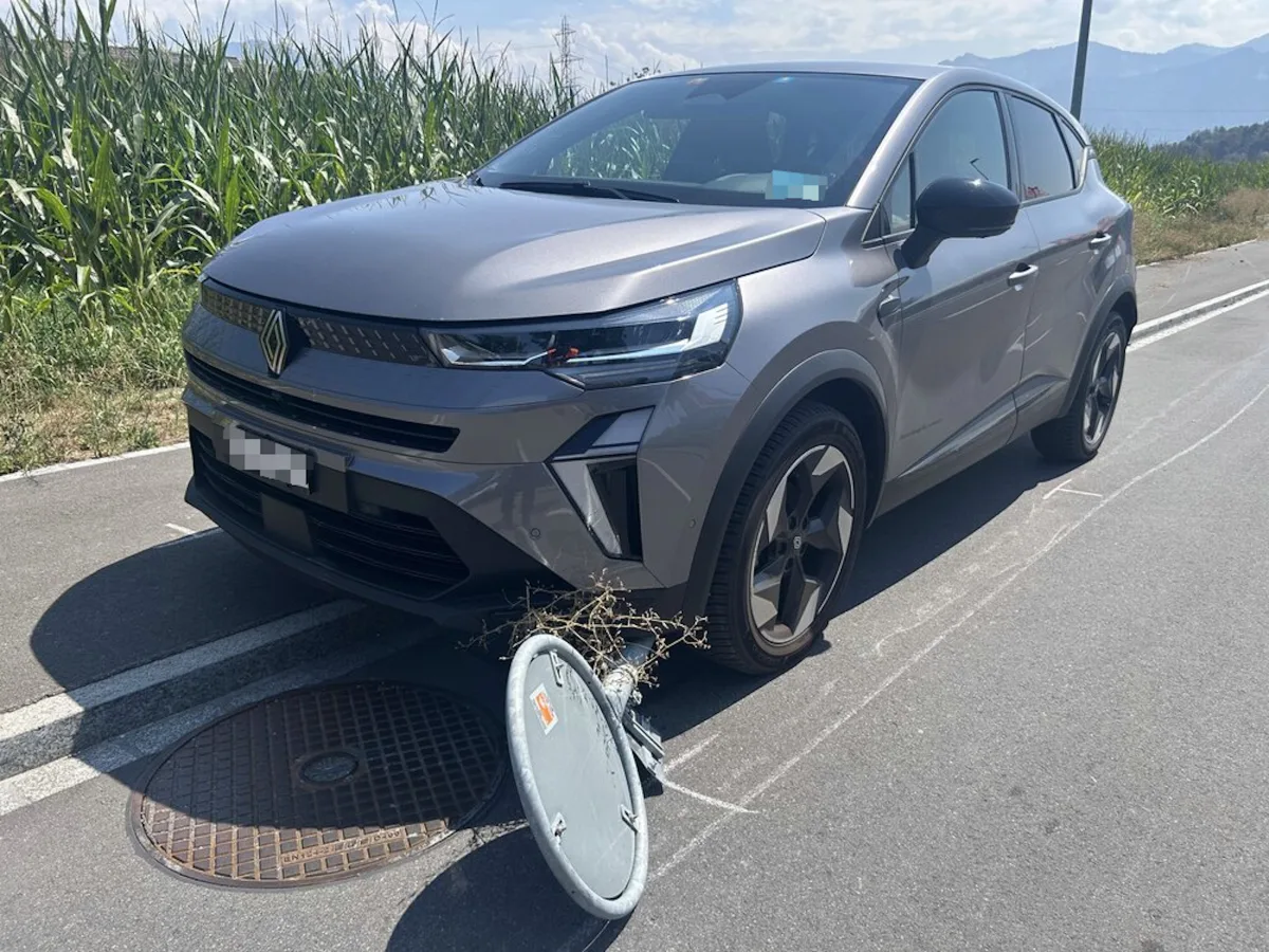 Ein graues Auto steht auf einer Landstraße. Daneben liegt ein umgekipptes Verkehrszeichen auf der Straße.
