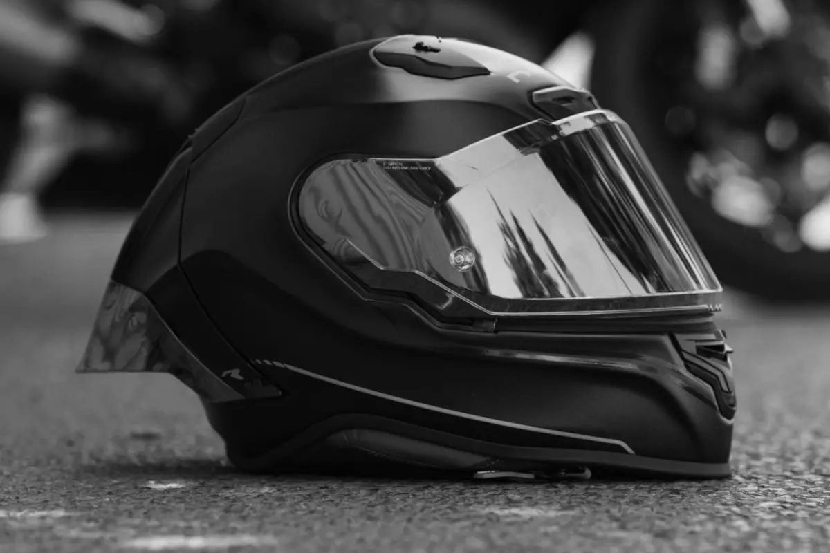 Ein schwarzer Motorradhelm liegt auf einer asphaltierten Straße. Der Hintergrund ist unscharf.