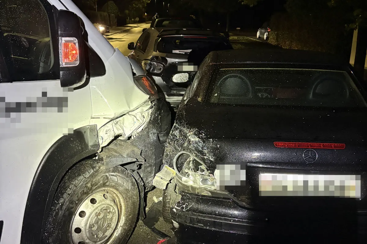 Ein weißer Transporter und ein schwarzer Mercedes sind bei einem Unfall auf einer nächtlichen Straße ineinander verkeilt. Mehrere Fahrzeuge sind betroffen und beschädigt.