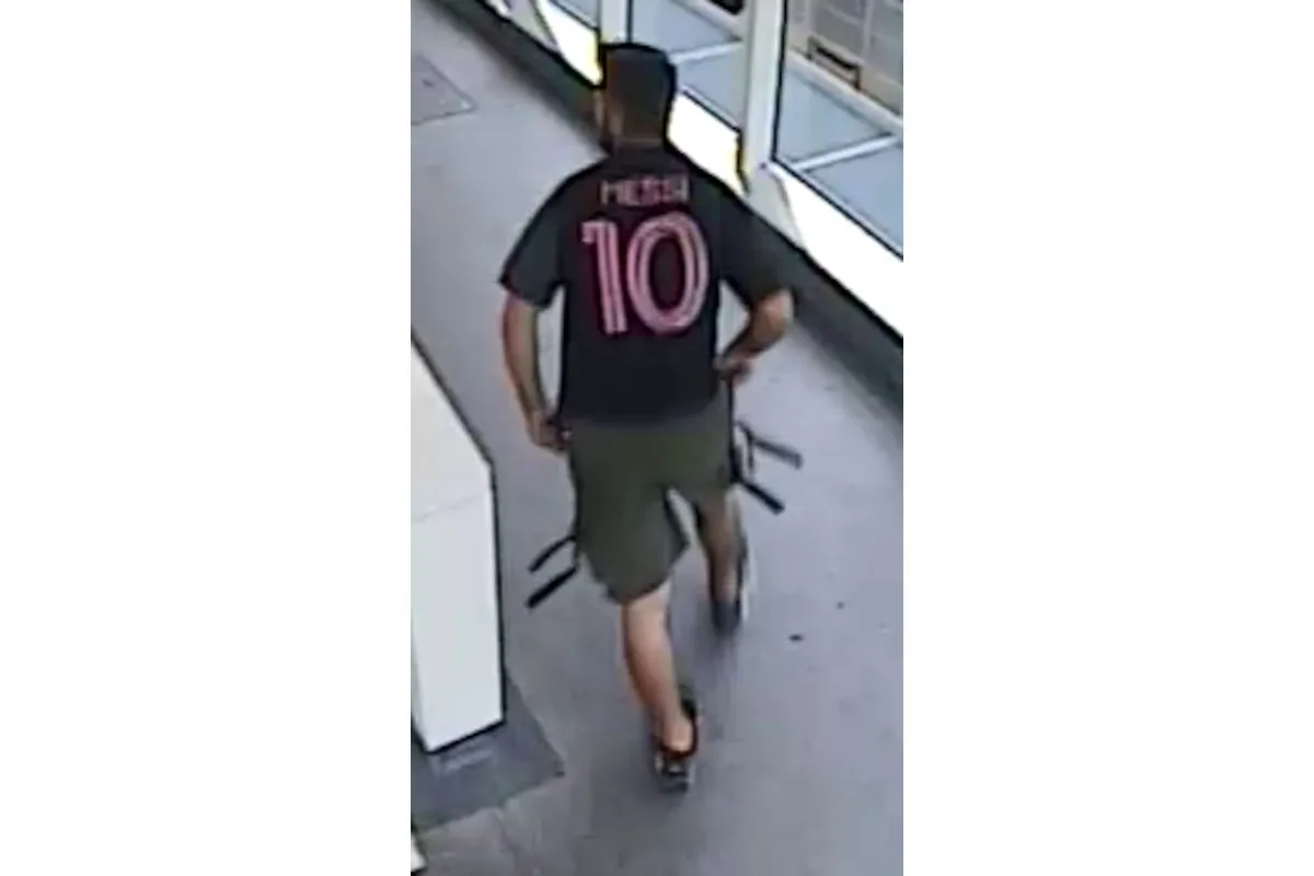 Eine männliche Person in einem Messi-Fußballtrikot geht durch einen Gang in einem Gebäude. Er trägt kurze Hosen und Sportschuhe.