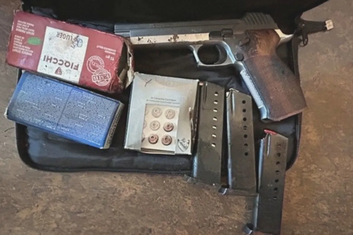 Im Bild ist eine Pistole zusammen mit mehreren gefüllten Magazinen und Schachteln mit Munition in einem geöffneten Koffer zu sehen. Die Anordnung lässt auf eine Sicherstellung durch die Polizei schließen.
