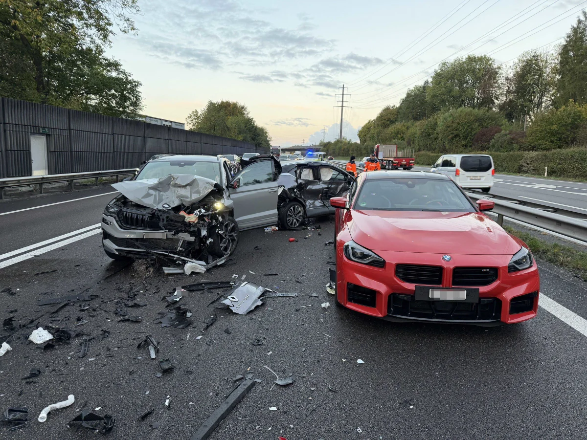Mehrere schwer beschädigte Fahrzeuge stehen nach einem Unfall auf der Autobahn. Trümmerteile liegen verstreut auf der Fahrbahn.