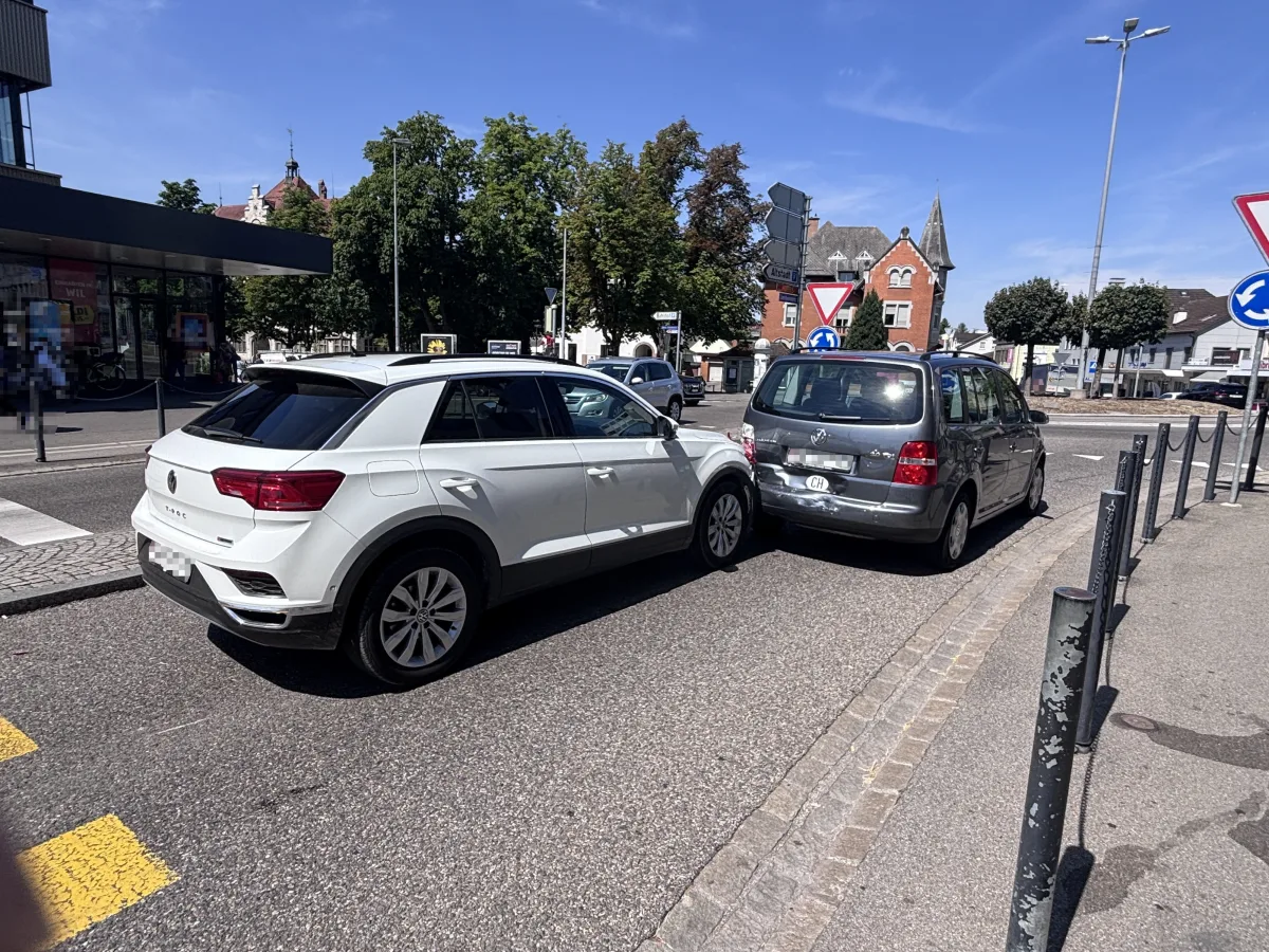 Ein weißer VW T-Roc und ein grauer VW Touran stehen nach einer leichten Kollision im Stadtzentrum. Die Autos sind an einem Kreisverkehr zu sehen.