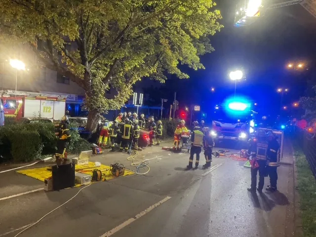 Zahlreiche Rettungskräfte sind an einem nächtlichen Unfallort in der Stadt versammelt. Beleuchtung und Fahrzeugfronten sind erkennbar.