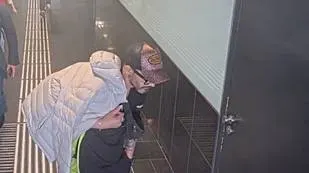 Eine Person trägt eine Jacke über den Schultern und steht vor einer verschlossenen Tür in einem Gebäude.