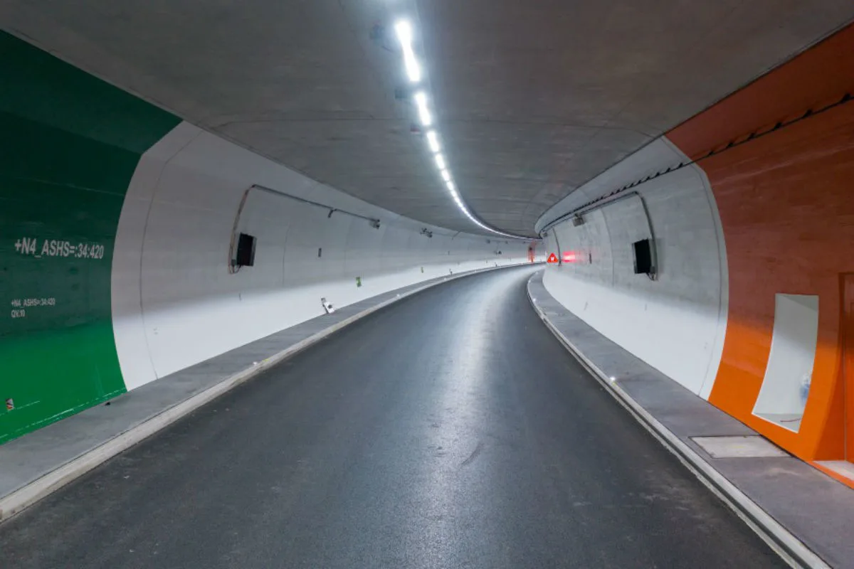 Der Tunnel ist menschenleer und zeigt einen geschwungenen Straßenverlauf. Die Wände sind teils grün und orange gestrichen.