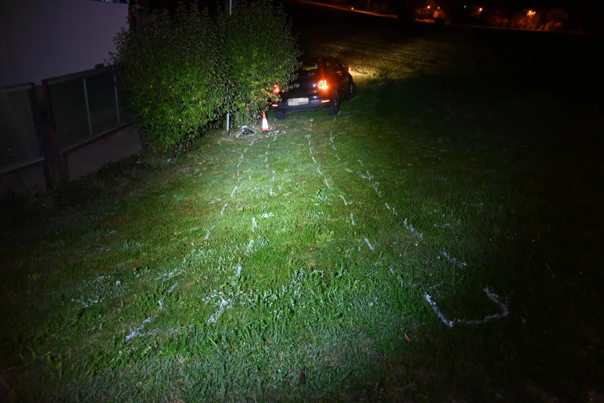 Ein Fahrzeug steht bei Nacht auf einer Wiese, im Gras sind deutliche Reifenspuren sichtbar, die von der Straße führen.