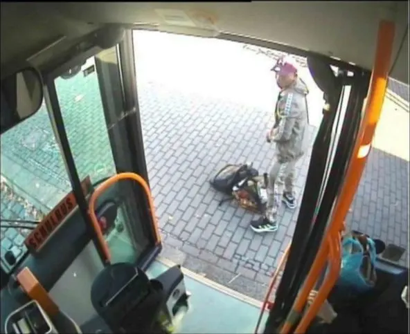Eine Überwachungskamera zeigt eine Person mit Taschen, die einen Bus verlässt. Der Innenraum des Busses ist teilweise sichtbar.