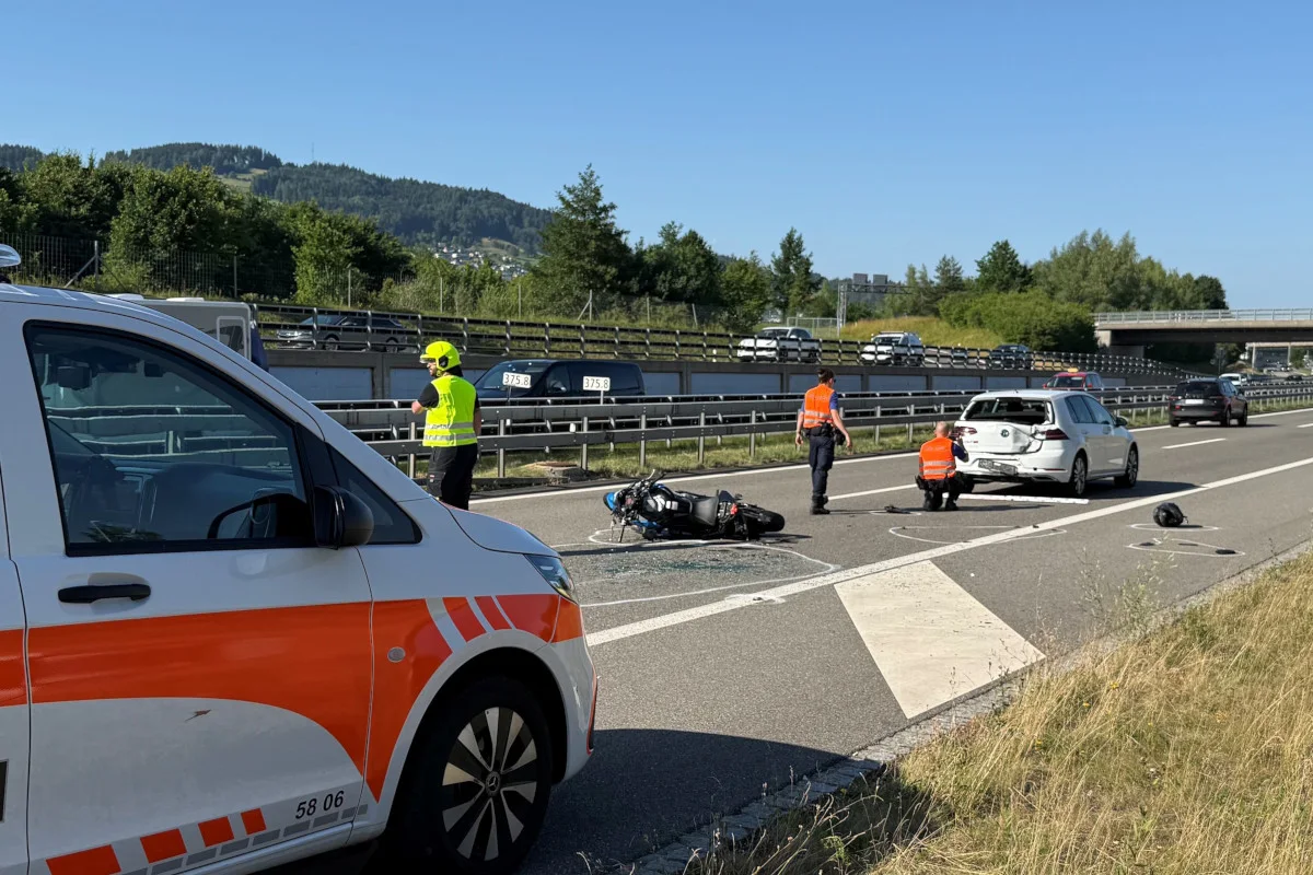 Ein Motorrad liegt auf der Autobahn neben einem beschädigten weißen Pkw. Polizei sichert die Unfallstelle ab.