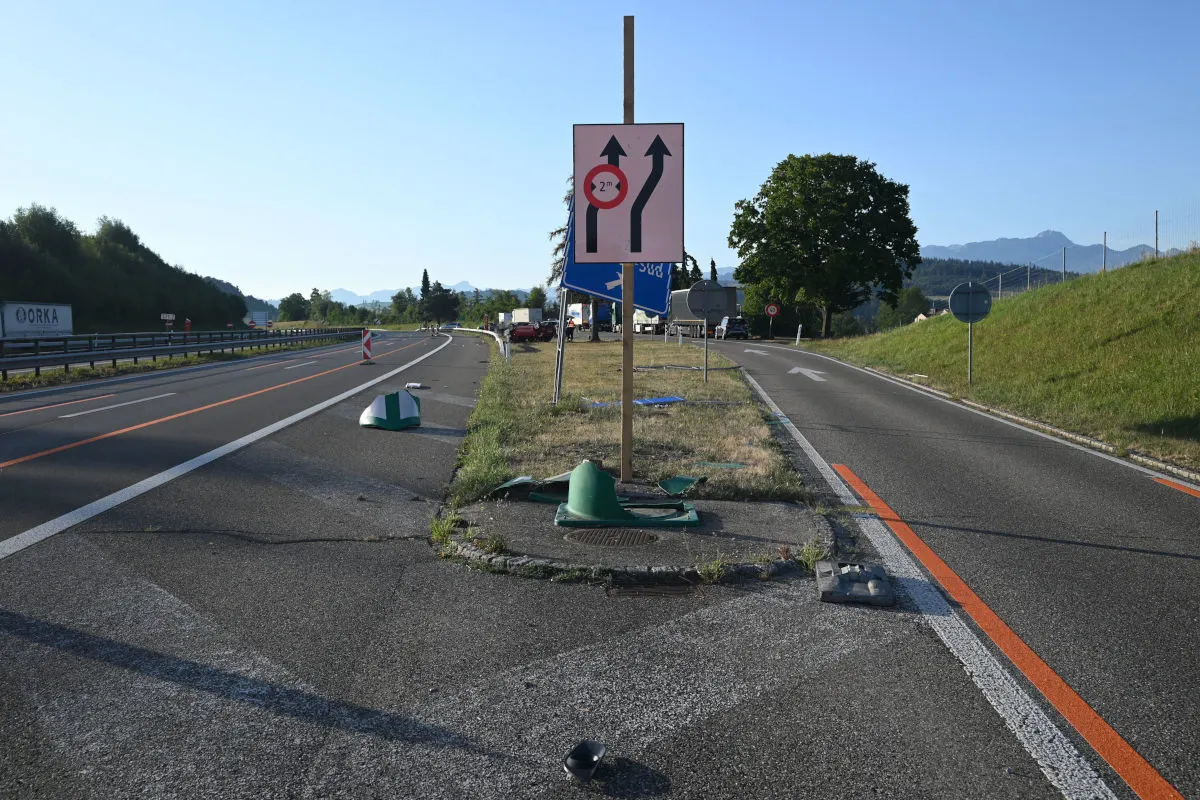Ein zentrales Verkehrsschild auf einer Abzweigung ist erheblich beschädigt. Umgebend sind Fahrbahnen und Grünflächen.