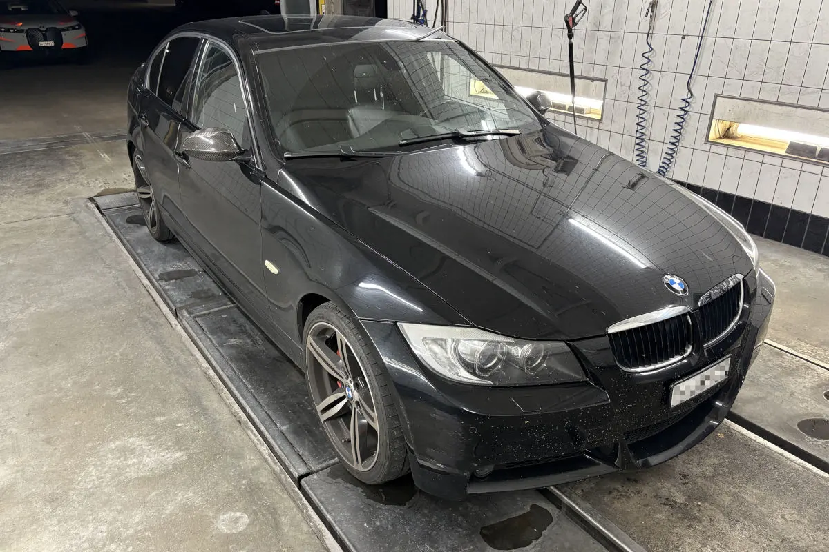 Ein schwarzer BMW parkt in einer Waschanlage. Im Hintergrund sind Details einer Garage zu sehen.