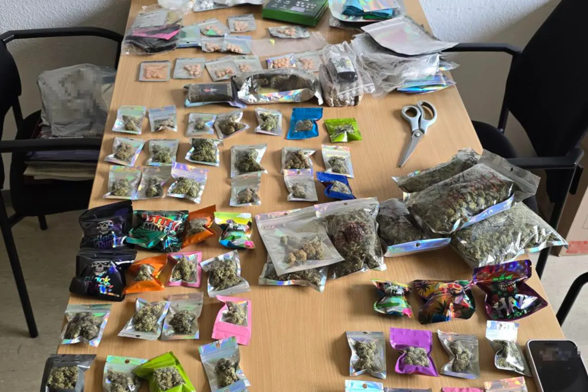 Auf einem Tisch liegen zahlreiche Plastiktüten mit verschiedenen Drogen und einer Schere. Daneben liegt eine gefüllte Plastiktüte auf einem Stuhl.