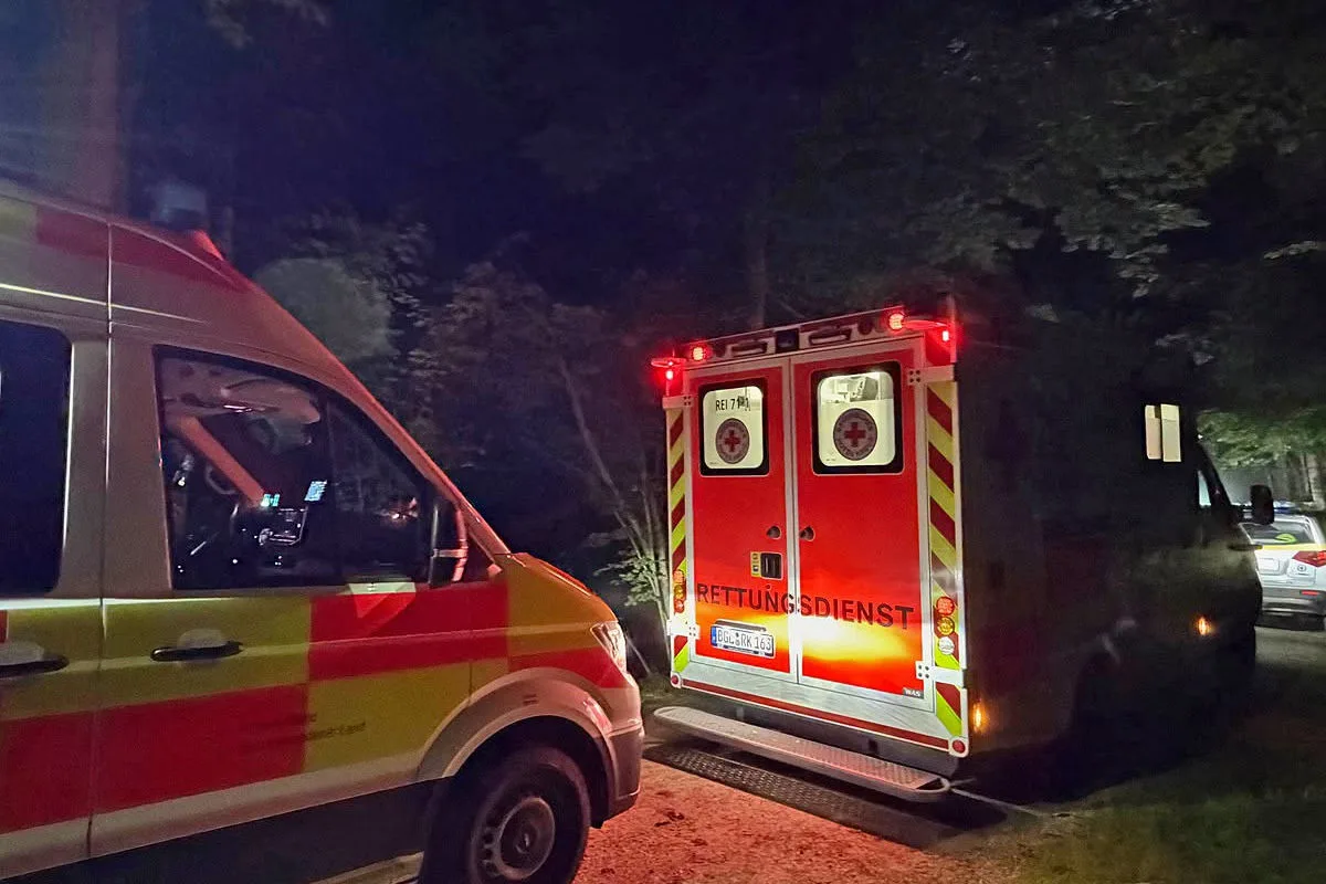 Zwei Krankenwagen stehen nachts vor einem Waldweg mit eingeschaltetem Blaulicht. Ein Fahrzeug ist von vorne, das andere von hinten zu sehen.